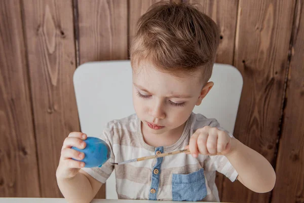 Bambino che dipinge uova colorate per Pasqua su backgroun di legno — Foto Stock