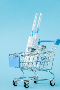 Mavi arka planda alışveriş arabası tıbbi enjeksiyon. Creati