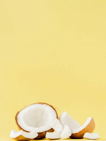 close up fresh coconut pieces isolated on a yellow background, tropical fruit concept, flat lay, pop art, copy space