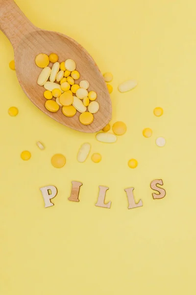 Pastillas amarillas redondas de vitaminas en cuchara sobre un fondo amarillo, espacio para copiar —  Fotos de Stock