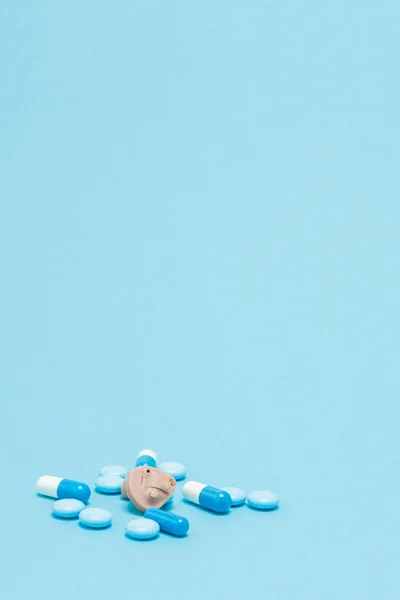 Audífono y pastillas azules sobre fondo azul. Concepto médico, farmacéutico y sanitario. Copiar espacio. Lugar vacío para texto o logotipo —  Fotos de Stock