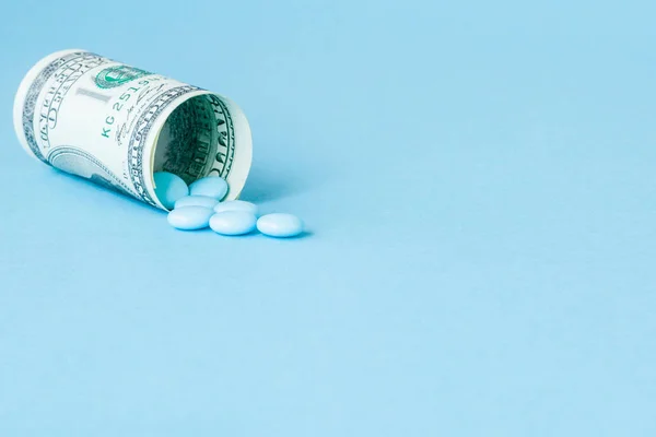 Dollar d'argent enroulé avec des pilules coulant isolé sur bleu b — Photo