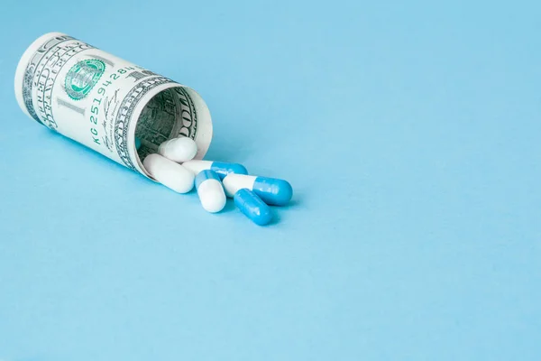 Dinero dólar enrollado con pastillas que fluyen aisladas en azul b — Foto de Stock