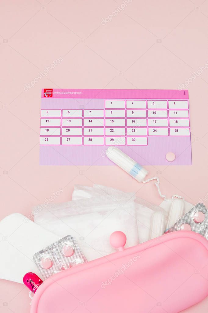Tampon, feminine, sanitary pads for critical days, feminine calendar, pain pills during menstruation on a pink background. Tracking the menstrual cycle and ovulation