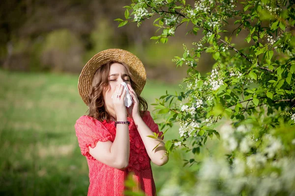 Młoda dziewczyna dmuchanie nosa i kichanie w tkance przed kwitną — Zdjęcie stockowe