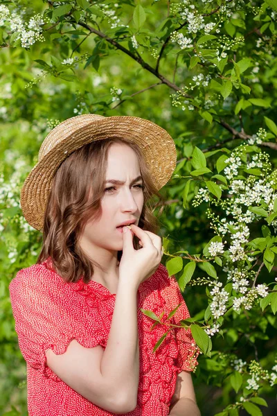 Mladá dívka smrká nosem a kýchá v tkáni před kvetoucím stromem. Sezónní alergeny postihující lidi. Krásná dáma má rinitidu. — Stock fotografie