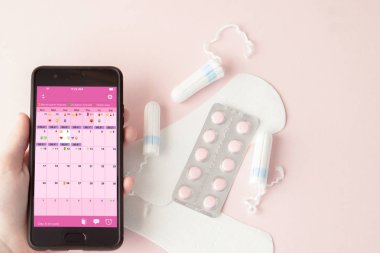 Tampon, kadınsı, kritik günler için hijyenik pedler, dişi takvimi, pembe arka planda regl sırasında ağrı kesiciler. Adet döngüsü ve yumurtlama takibi