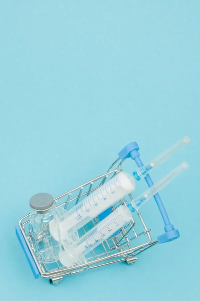 Medische injectie in de winkelwagen op blauwe achtergrond. Creatief idee voor de kosten van de gezondheidszorg, drogisterij, ziektekostenverzekering en farmaceutisch bedrijf business concept. Ruimte kopiëren — Stockfoto