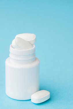 Hap hap şişesi üzerinde mavi arka plan dışarı dökülmesini kapatın. Tıp, sağlık sigortası veya eczane konsepti