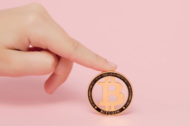 Kadın, pembe bir sırtında parıldayan yeni altın bitcoin ile el ele tutuşuyor.