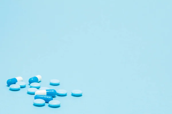 Pilules bleues éparpillées sur la table bleue. Maquette pour des offres spéciales un — Photo