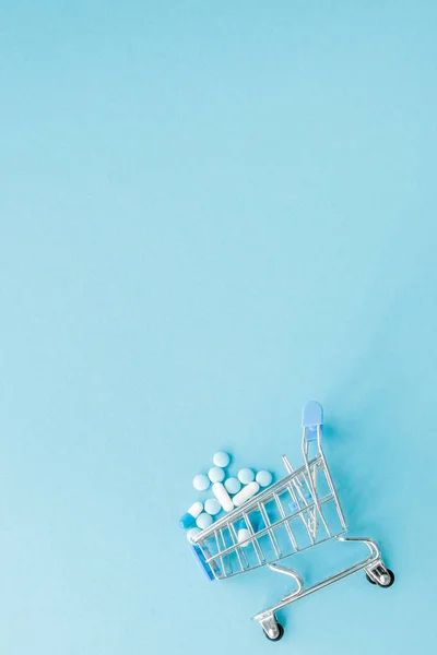 약 고 파란색 배경에 쇼핑 트롤리입니다. 의료 비용, 약국, 건강 보험 및 제약 회사 사업 개념에 대 한 창의적인 아이디어. 공간 복사 — 스톡 사진