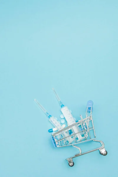 Hapları ve mavi backgrou üzerinde alışveriş arabası tıbbi enjeksiyon — Stok fotoğraf