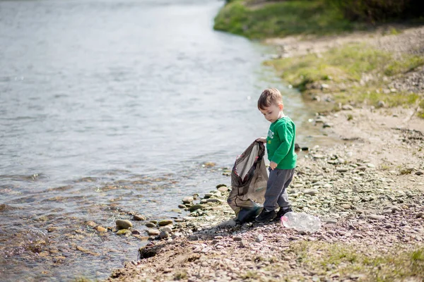 Umweltkonzept retten, ein kleiner Junge Müll sammeln und pl — Stockfoto