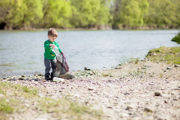 Salva concetto di ambiente, un bambino che raccoglie spazzatura e pl — Foto Stock