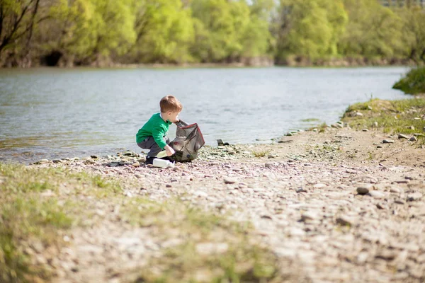 Salva concetto di ambiente, un bambino che raccoglie spazzatura e pl — Foto Stock