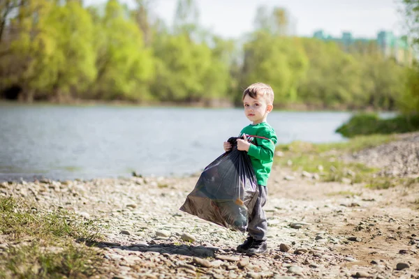 Umweltkonzept retten, ein kleiner Junge Müll sammeln und pl — Stockfoto