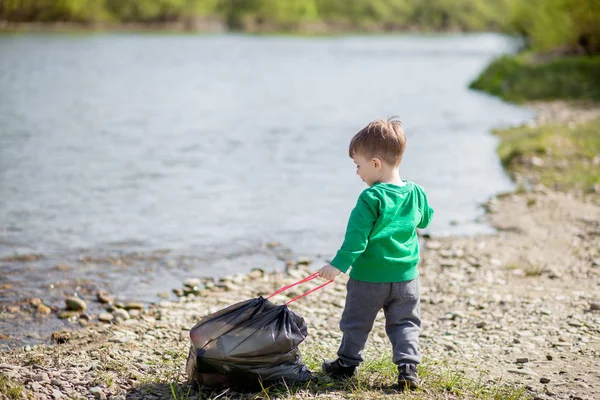 Umweltkonzept retten, ein kleiner Junge Müll sammeln und pl — Stockfoto