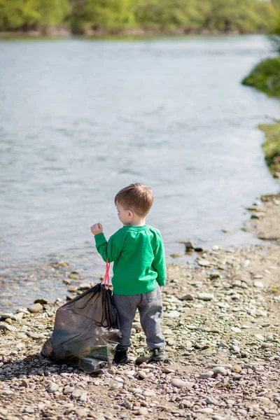 Salva concetto di ambiente, un bambino che raccoglie spazzatura e pl — Foto Stock