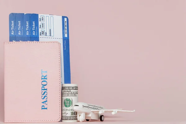 Paszport, dolary, samolot i bilet lotniczy na różowym tle. Tr — Zdjęcie stockowe