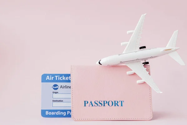 Passport, plane and air ticket on a pink background. Travel conc