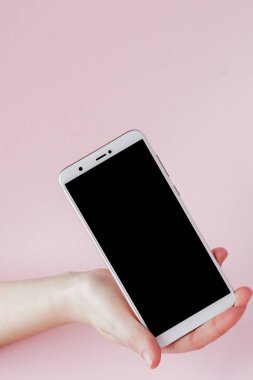 Pembe arka planda bir kadının elinde modern cep telefonu
