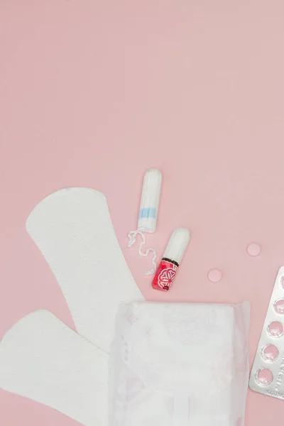 Almohadillas sanitarias y tampones y pastillas sobre fondo rosa. Mujer cr —  Fotos de Stock