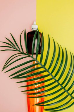 Parlak kare sarı ve pembe arka planda şişe güneş kremi. Denizde tatil konsepti, yaz zamanı. Üst görünüm, düz yatıyordu, Minimalizm, kopya alanı