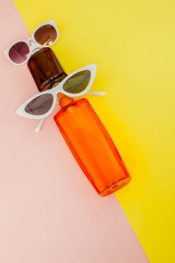 Parlak kare sarı ve pembe arka planda şişe güneş kremi. Denizde tatil konsepti, yaz zamanı. Üst görünüm, düz yatıyordu, Minimalizm, kopya alanı