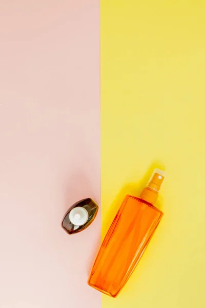 Пляшковий сонячний блок на яскравому квадратному жовтому і рожевому фоні. Зрозуміло — стокове фото