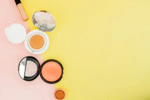 Make up prodotti versando su uno sfondo giallo brillante e rosa con spazio copia — Foto Stock