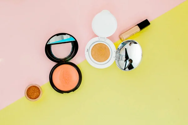 Trucchi i prodotti che versano sopra ad un backgro giallo e rosa luminoso — Foto Stock