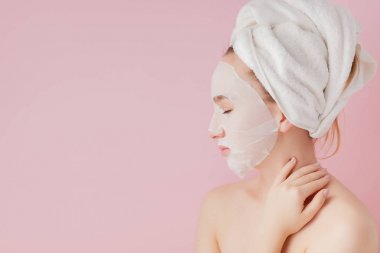 Güzel genç kadın kozmetik doku maske pembe bir arka plan üzerinde bir yüzünde uyguluyor. Sağlık ve güzellik tedavi ve teknoloji kavramı