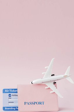 Pembe arka planda pasaport, uçak ve uçak bileti. Seyahat conc