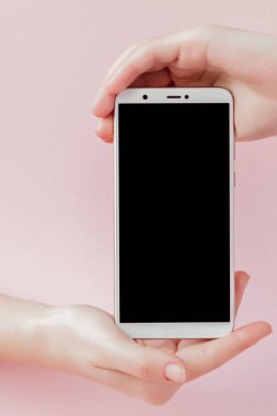 Pembe arka planda bir kadının elinde modern cep telefonu