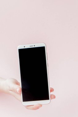 Pembe arka planda bir kadının elinde modern cep telefonu