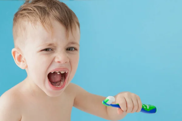 Retrato de niño pequeño con cepillo de dientes sobre fondo azul — Foto de Stock