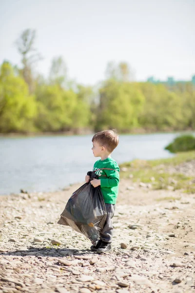 Umweltkonzept retten, ein kleiner Junge Müll sammeln und pl — Stockfoto