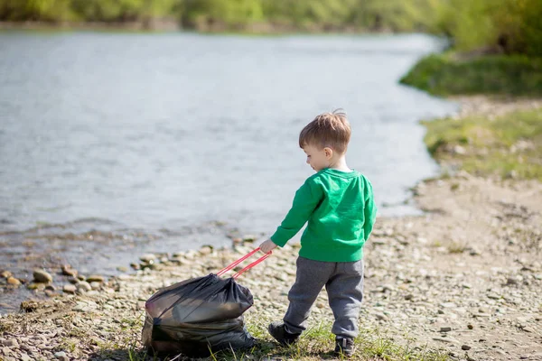 Umweltkonzept retten, ein kleiner Junge Müll sammeln und pl — Stockfoto