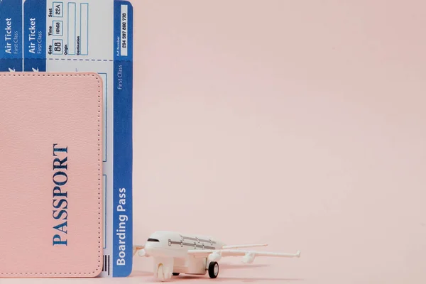 Passaporte, avião e bilhete de avião sobre fundo rosa. Conc. de viagem — Fotografia de Stock