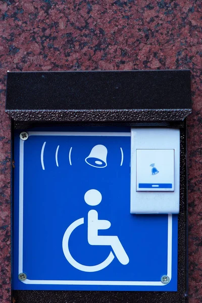 Handicapped access entrance pad mounted to a wall. Sign a button for a visa for people with disabilities