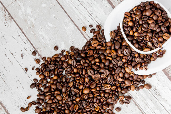 Black coffee in white cup and coffee beans on light wooden backg