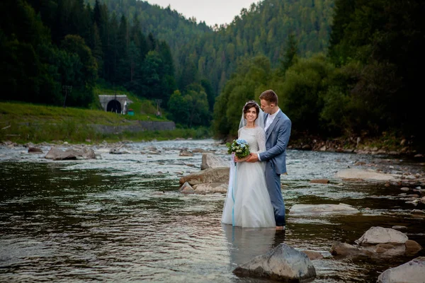 Sposi felici in piedi e sorridenti sul fiume. Luna di miele, foto per il giorno di San Valentino — Foto Stock