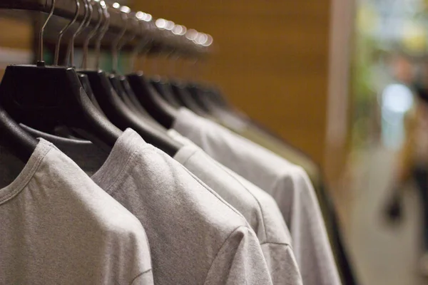 Camisetas grises en perchas en la tienda de ropa, vista de cerca — Foto de Stock