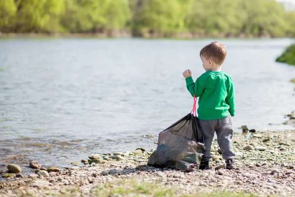 Salva concetto di ambiente, un bambino che raccoglie spazzatura e pl — Foto Stock