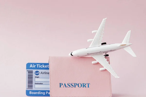 Passport, plane and air ticket on a pink background. Travel conc
