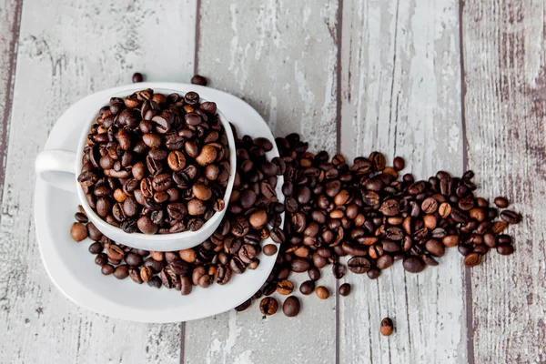 Black coffee in white cup and coffee beans on light wooden background. Top view, space for text — Stock Photo, Image