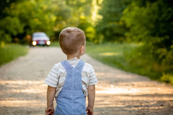 En liten pojke på en väg i skogen. Faran på vägen. Barnet är i fara på vägen — Stockfoto