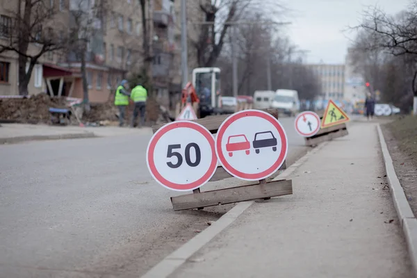 Road signs, detour, road repair on street background, truck and excavator digging hole