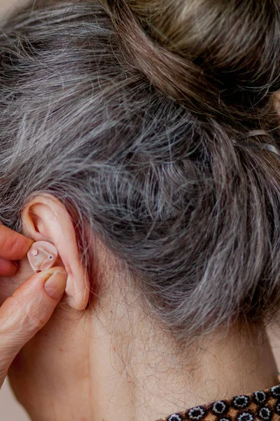 Gros plan femme âgée insérant prothèse auditive dans ses oreilles — Photo